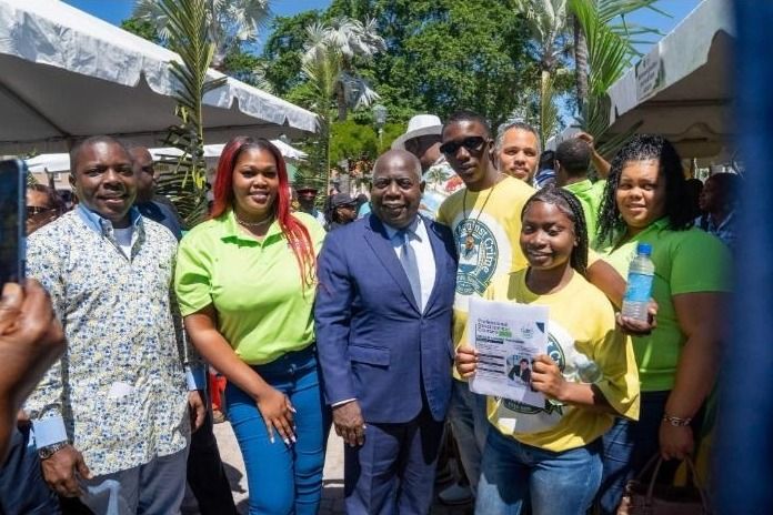 Attendees in yellow and green shirts pose with a man in a navy suit at the expo