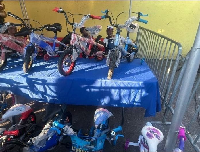 Children's bicycles wrapped in plastic are displayed on a blue table and on the ground