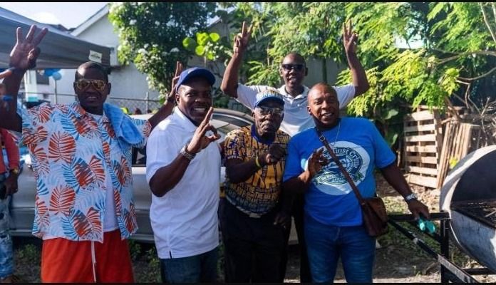 Four men smile and flash peace signs outdoors at the Father's Day event